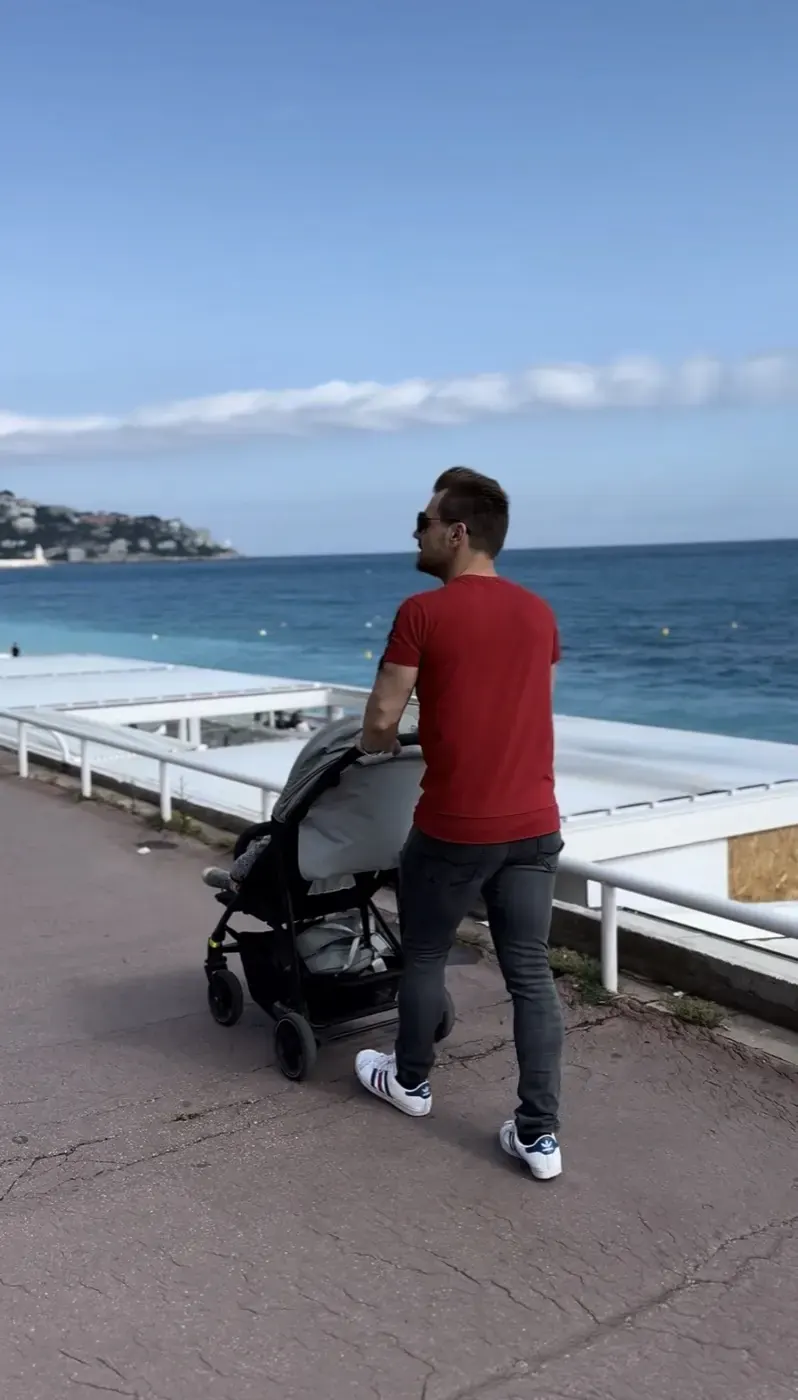 Vater schiebt den Kinderwagen über eine Promenade am Meer