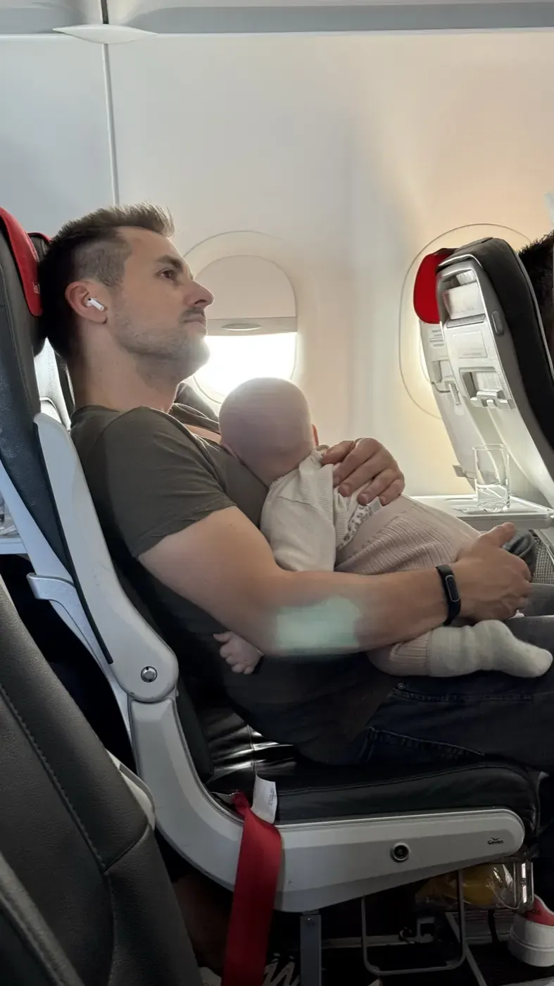 Vater hält das schlafende Baby im Flugzeug